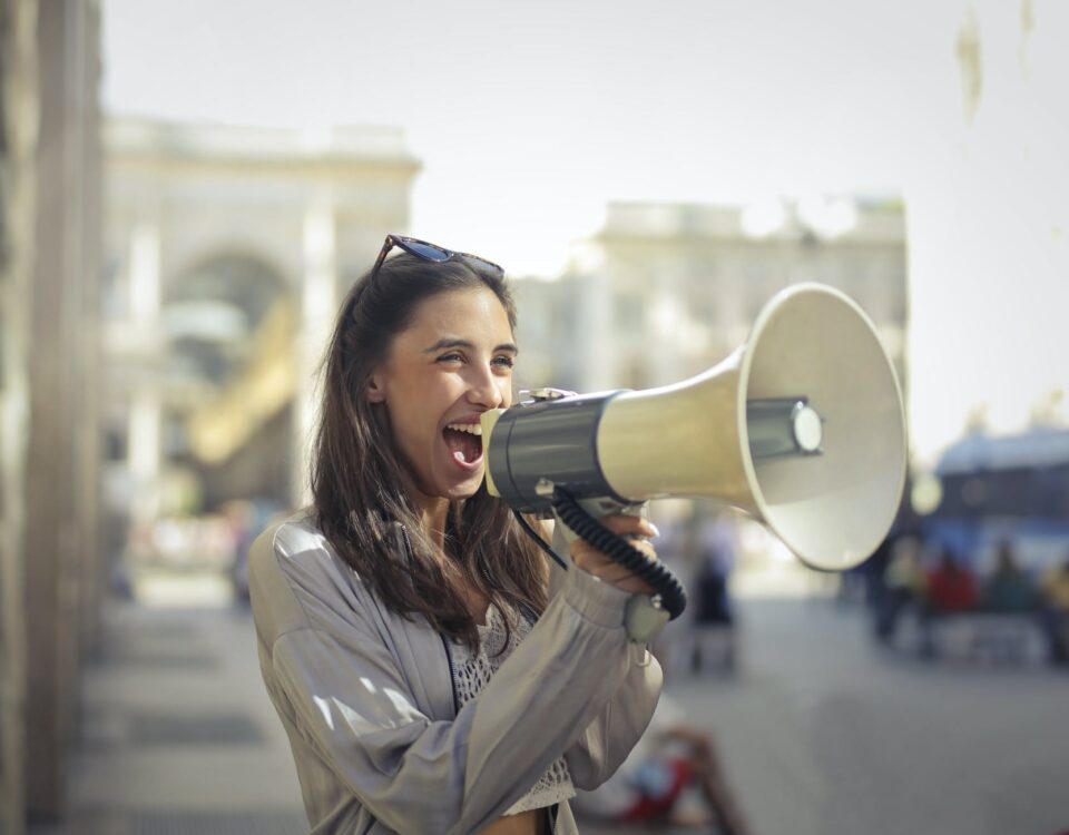 cheerful young woman screaming into megaphone